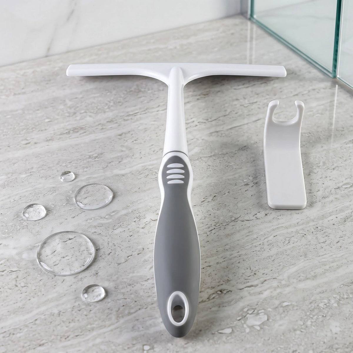 A white and gray glass wiper and a white hook on a marble surface with water droplets.