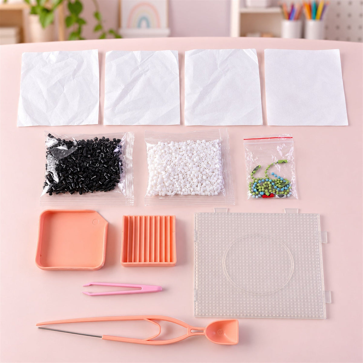 A flat lay displaying all components of the fuse bead kit, including bags of black, white, and colorful beads, tools, and