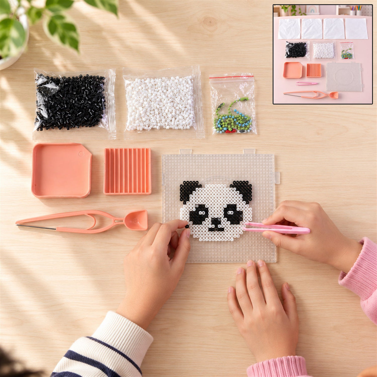 Overhead view of hands assembling a panda design with fuse beads on a pegboard, with an inset showing the entire kit