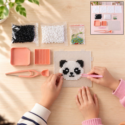 Overhead view of hands assembling a panda design with fuse beads on a pegboard, with an inset showing the entire kit
