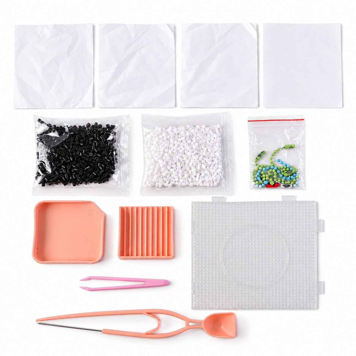 Top-down view of the craft kit contents, showing plastic bags of beads, pink trays, a clear pegboard, and crafting tools.