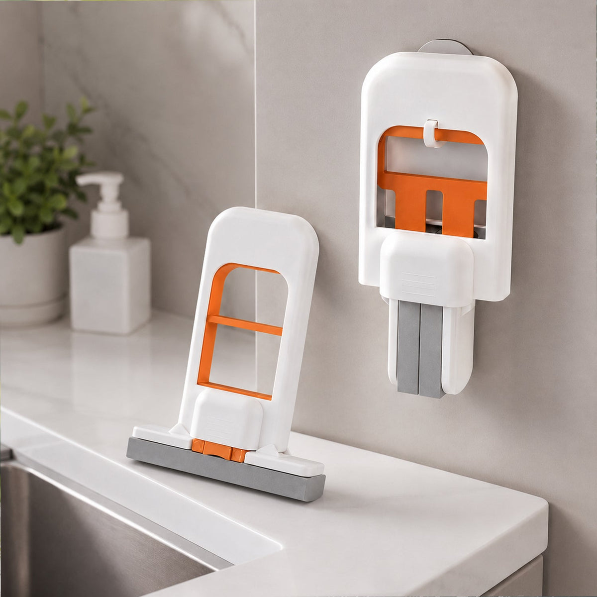 The white and orange mini mop handle and a separate grey sponge head are displayed side-by-side on a light wooden surface.