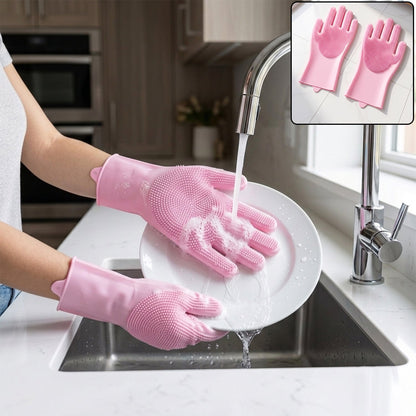 Hands wearing pink silicone gloves with scrubbing bristles washing a white plate under running water in a kitchen sink.