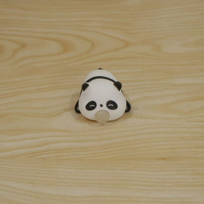 The panda squishy toy, with a small clear bubble, is centered on a light wooden table.