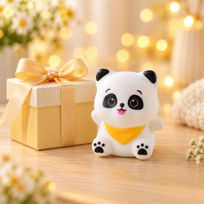 The unlit panda night light sits next to a golden gift box tied with a ribbon, surrounded by soft lights.