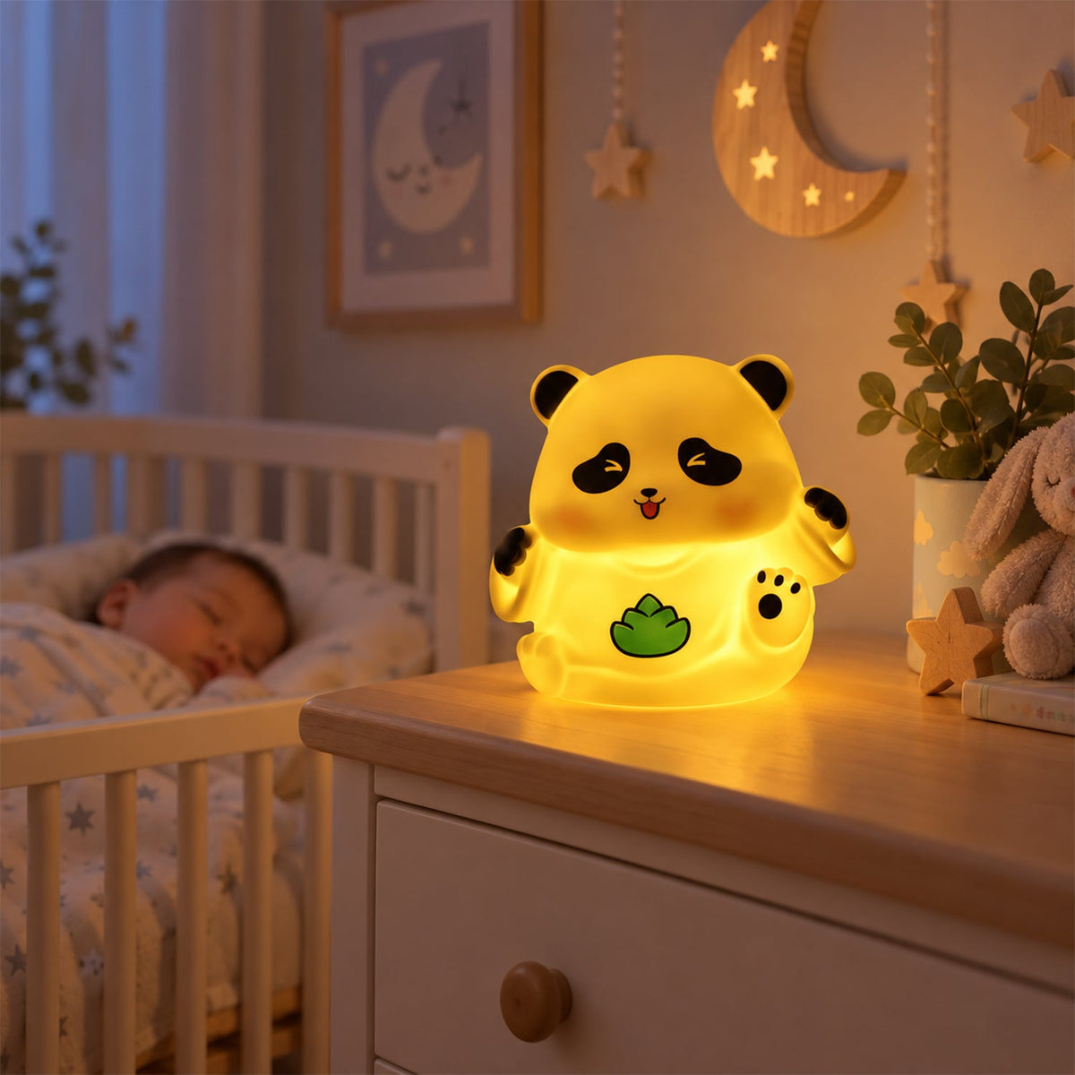 A glowing panda night light on a wooden dresser next to a sleeping baby in a crib.
