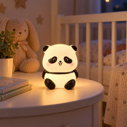 A glowing panda night light sits on a white bedside table next to a stuffed bunny and a plant.