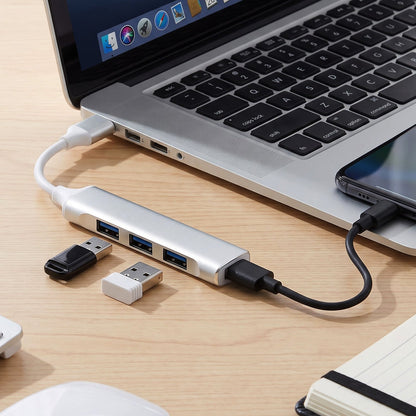 Silver 4-port USB hub connected to a laptop, with two USB drives plugged in