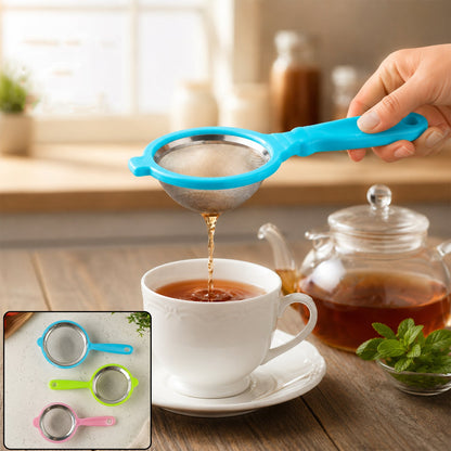 A hand holds a blue tea strainer, pouring tea into a white cup, with a teapot and mint nearby.