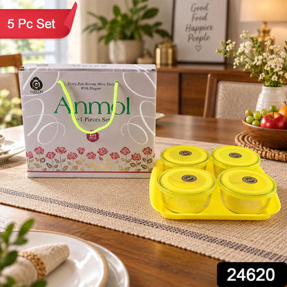 A set of four glass bowls with yellow lids on a tray, next to a decorative gift box.