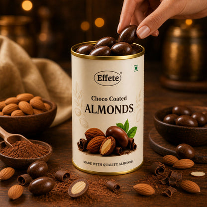 A hand reaching into a tin of Effete Choco Coated Almonds, with almonds and cocoa powder on the table.