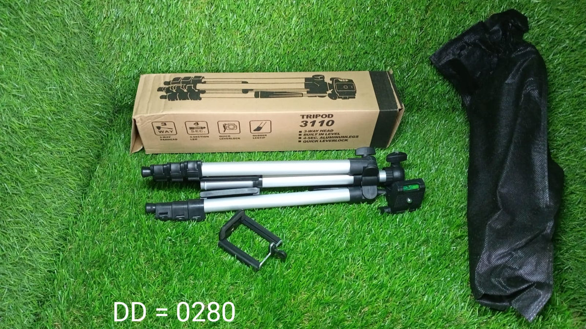 A silver and black tripod, its carrying bag, and its cardboard box are laid out on a vibrant green grassy surface.
