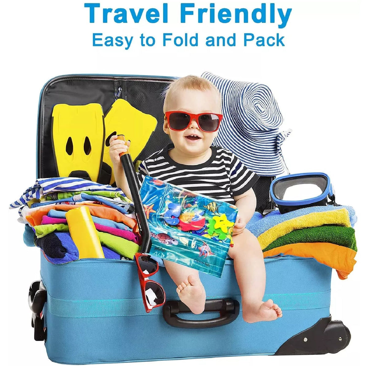 A baby in sunglasses sits in an open blue suitcase, holding a folded water mat, surrounded by travel items.
