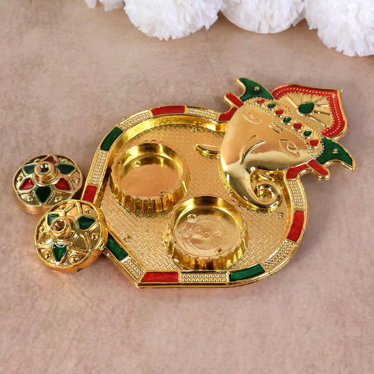 An angled view of the golden Ganesh pooja thali, showing the two empty round containers and the intricate textured surface.