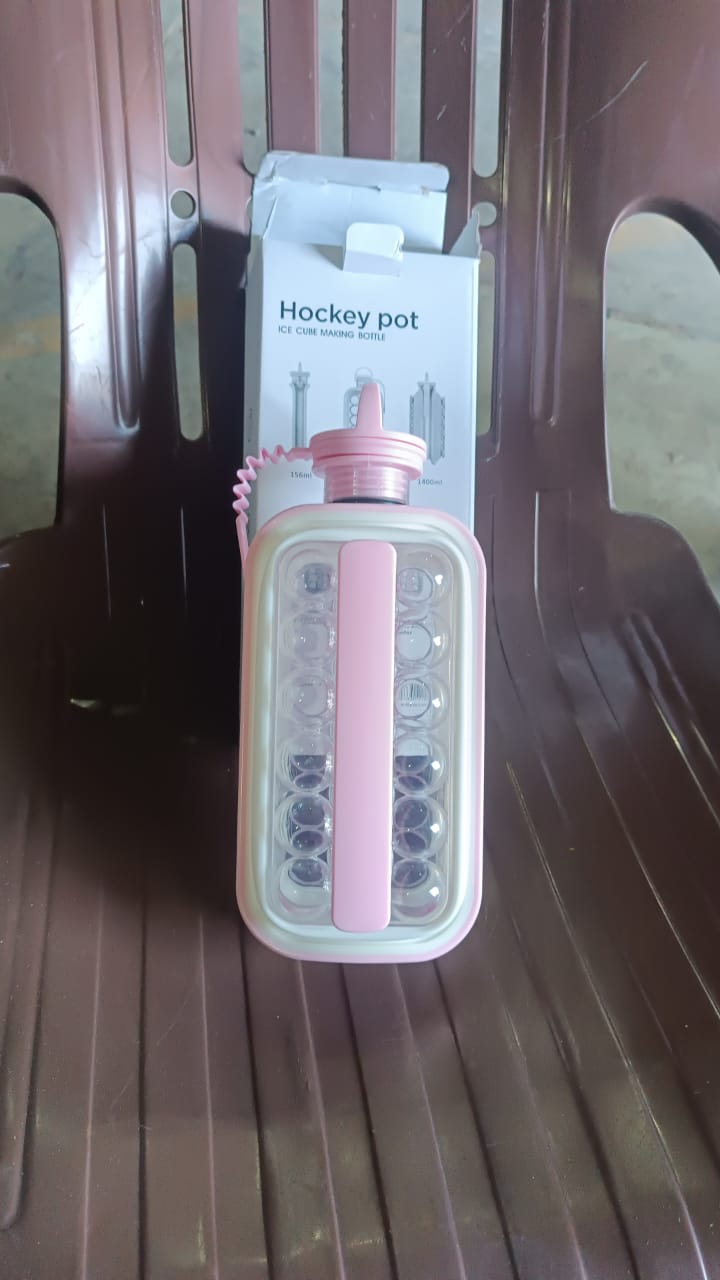 A pink ice ball maker bottle with its packaging box sits on a brown plastic chair, showing the product name and design.