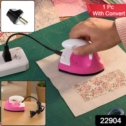 A hand holds a pink and white mini iron on fabric, with a black converter plug and a red banner saying "1 Pc With Convert".
