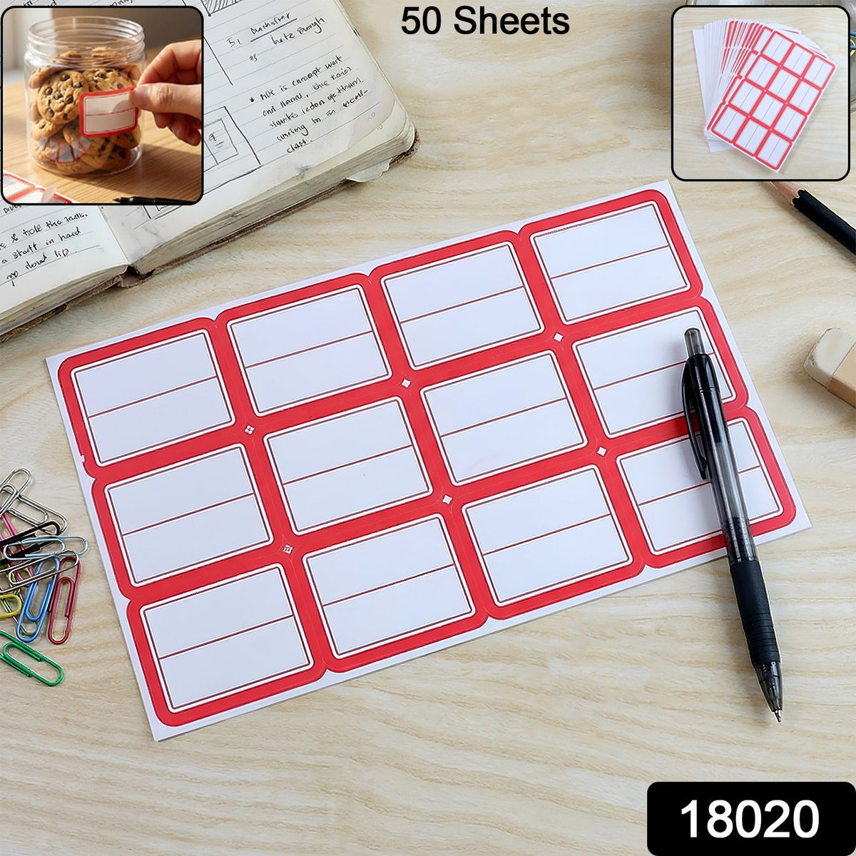 A sheet of 12 red-bordered white writable labels on a wooden desk with a pen, paper clips, and a jar of cookies.