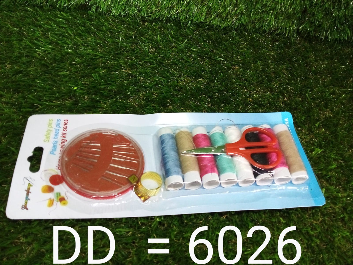 A packaged sewing kit with various colored threads, a thimble, scissors, and a needle case, resting on green artificial