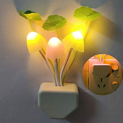 A mushroom night light with glowing yellow caps and green leaves is plugged into a wall, with an inset showing the plug