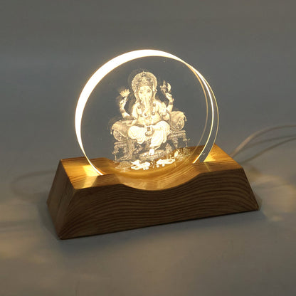 The Ganesha 3D illusion lamp with a clear acrylic panel and wooden base, brightly illuminated.