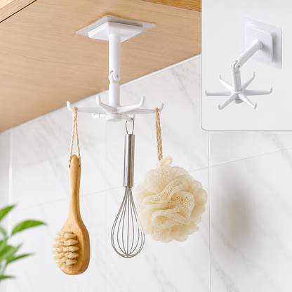 A white 360-degree rotating hook with six prongs hangs from a wooden cabinet, holding a wooden brush, whisk, and loofah.