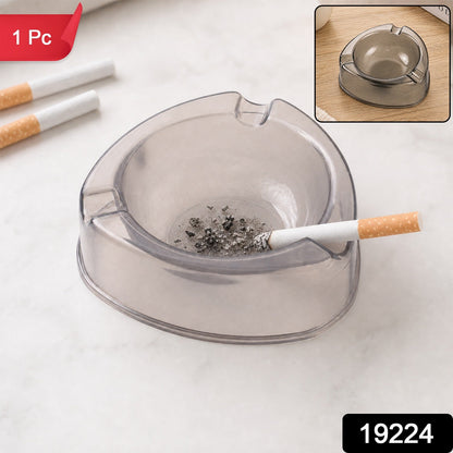 A sky blue transparent plastic ashtray is centered among cigarettes, coffee beans, sugar cubes, and a lighter.