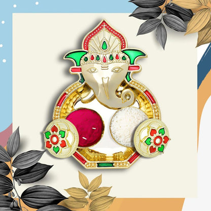 A golden Ganesh pooja thali with two small round containers, one filled with red powder and the other with white rice,