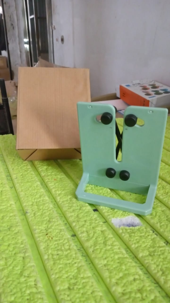 A mint green X-rod knife sharpener and a brown cardboard box sit on a bright green textured surface.