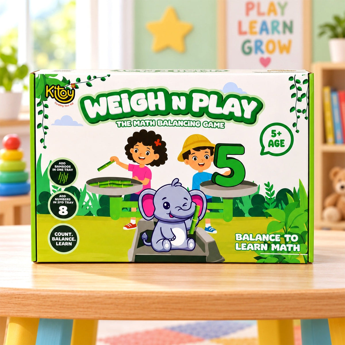 A green and white box for Kitoy Weigh N Play, a math balancing game featuring a cute winking elephant.