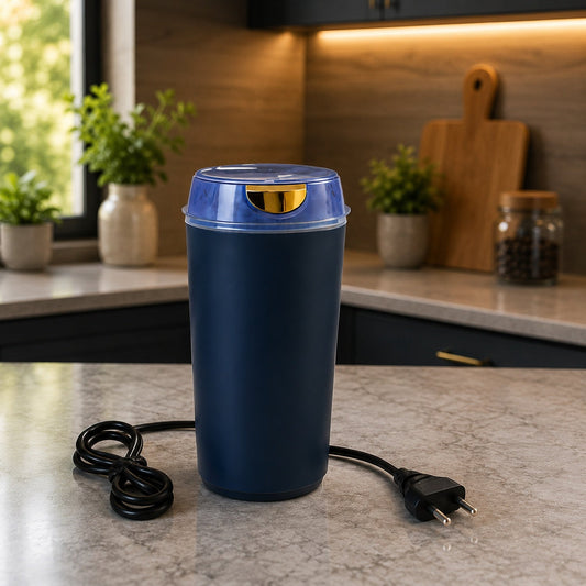 A dark blue electric grinder with a clear lid and gold accent sits on a kitchen counter with a black power cord.