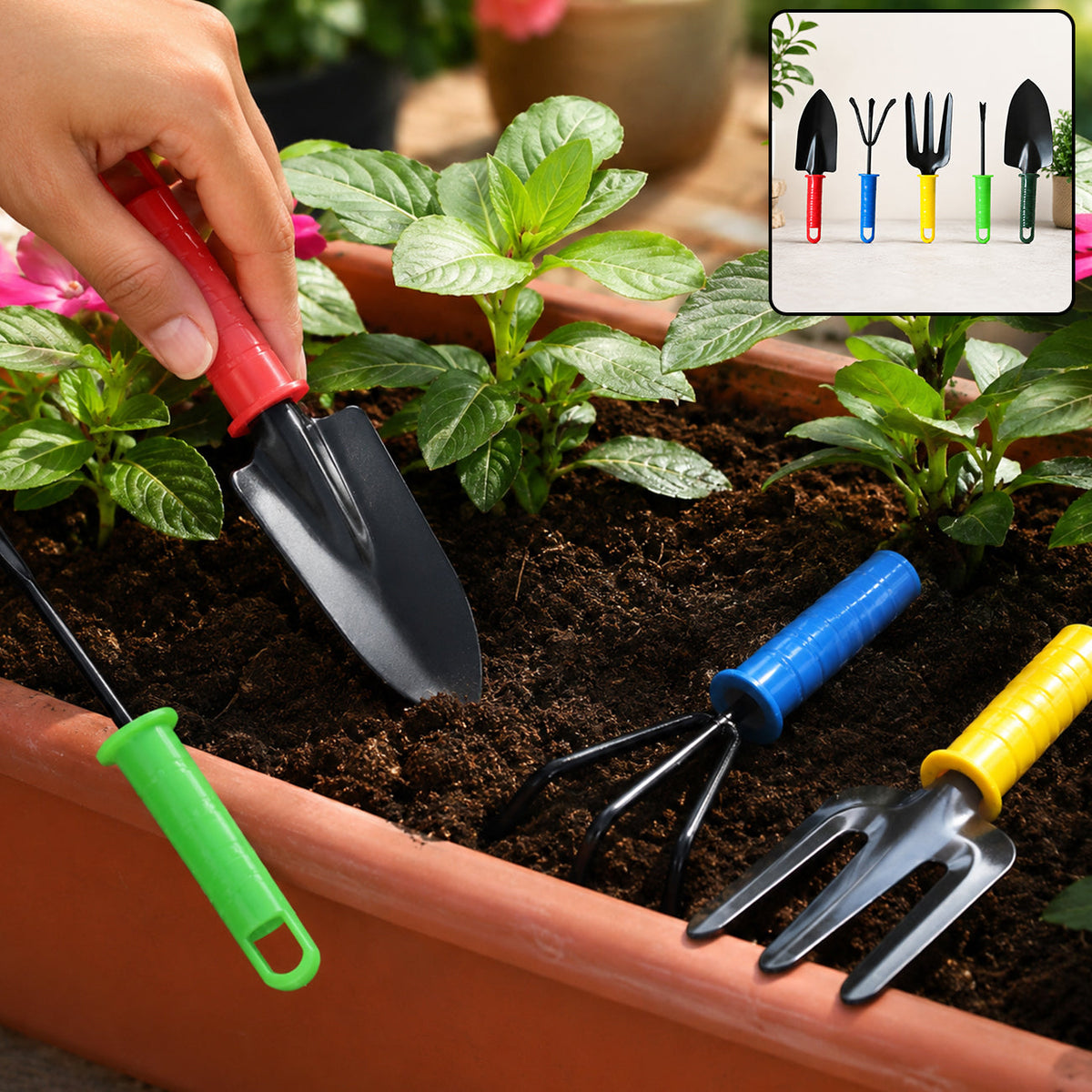 A hand holds a red-handled trowel in a planter with other colorful gardening tools and green plants.