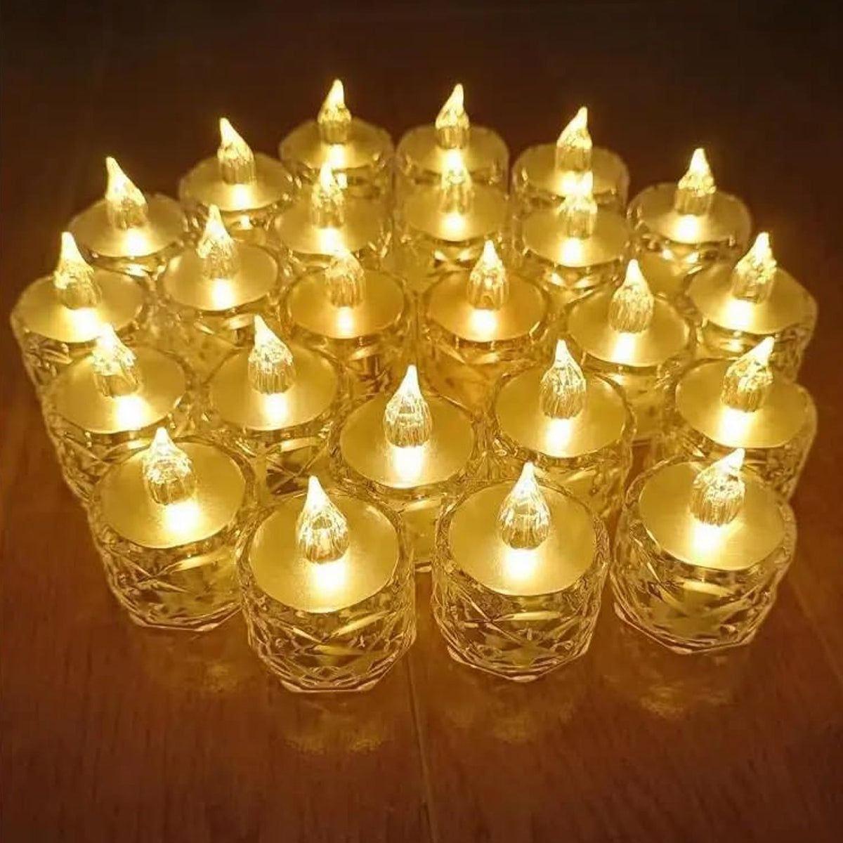 A cluster of twenty-four clear acrylic flameless LED tealight candles with warm yellow light on a wooden floor.
