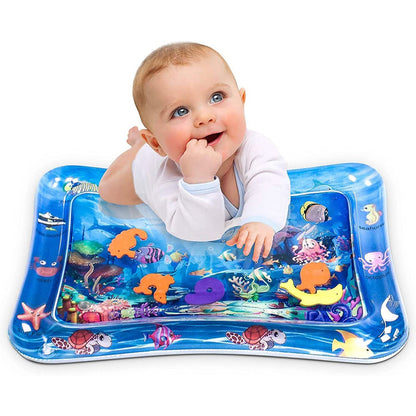 A baby in a white long-sleeve onesie smiles while doing tummy time on a blue water play mat.