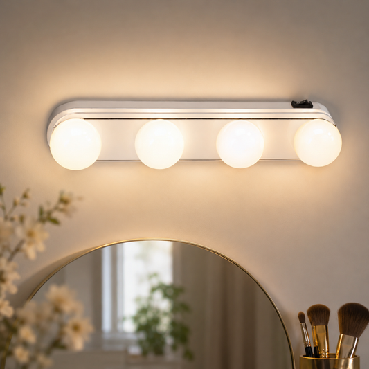 A white LED vanity light with four round bulbs is mounted above a gold-rimmed mirror, with flowers and brushes in the