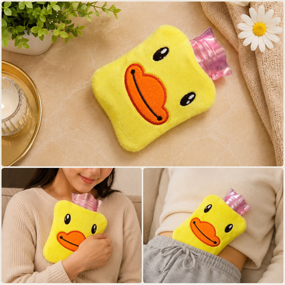 A yellow duck-shaped hot water bottle with a pink plastic insert on a marble surface with a candle and plant.