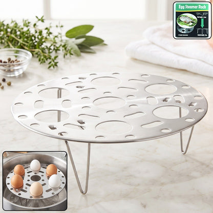 A silver metal egg steamer rack with three legs rests on a white marble surface, with an inset showing the rack in a pot.