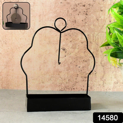 A black metal mosquito coil holder with a rectangular base is displayed against a textured beige wall.