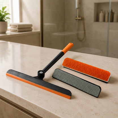 An orange and black squeegee with two interchangeable scrubber pads, one orange and one gray, on a bathroom counter.