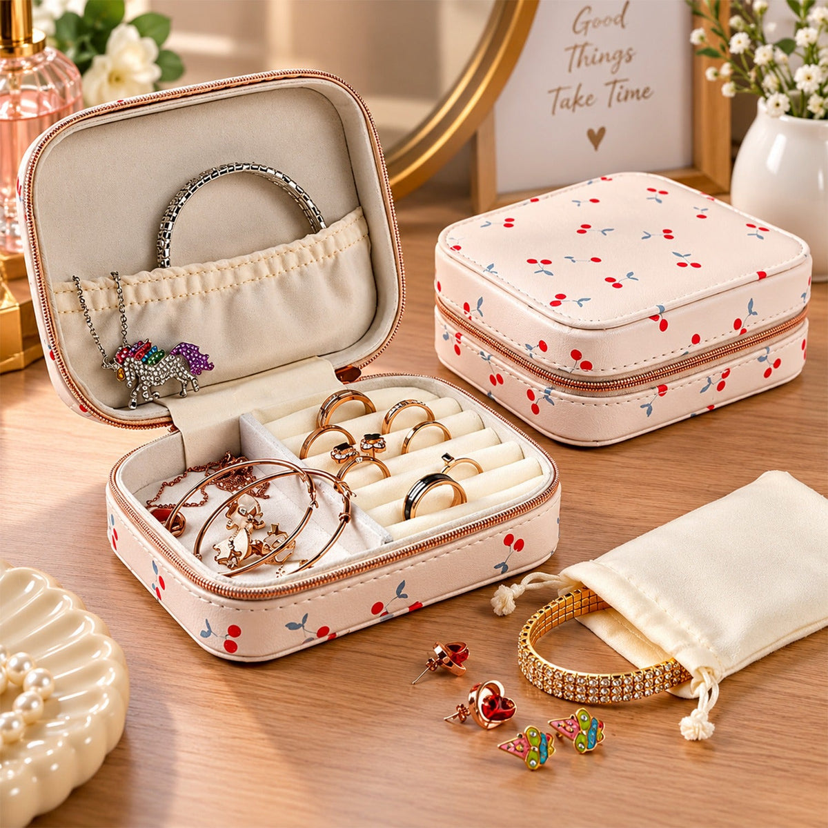 An open cherry print jewelry organizer displays rings, bracelets, and a unicorn necklace on a wooden surface.