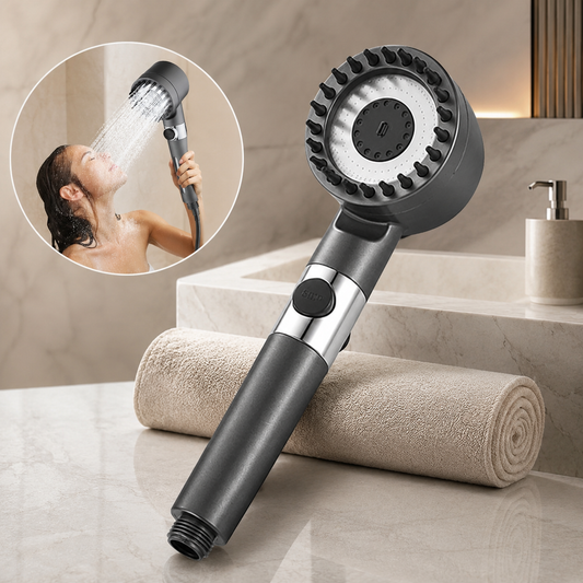A dark gray shower head with a wide face and rubber bristles, next to a rolled towel, with an inset of a woman showering.