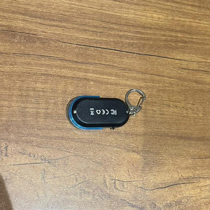 A black and blue personal safety alarm keychain with a silver carabiner clip is attached to a black leather handbag.