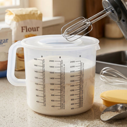 A clear plastic measuring jug filled with a light liquid, with an electric mixer above it.
