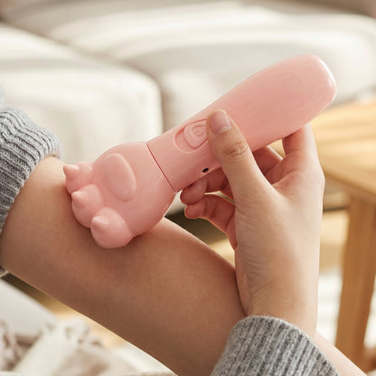 A person's hand holds a pink bear paw massager against their forearm, showing the device's textured paw end.