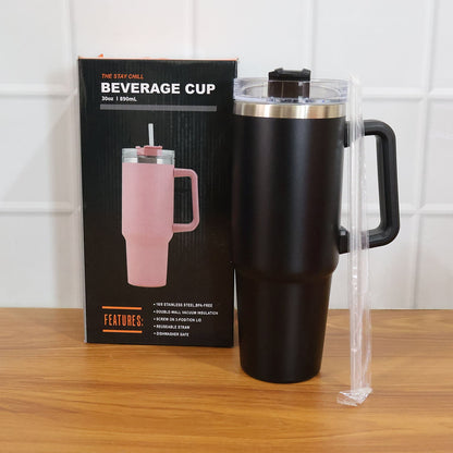 Black insulated travel mug with handle, lid, and straw next to its product box featuring a pink version of the mug.