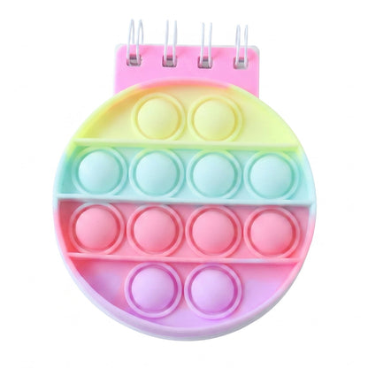 A rainbow pop-it fidget notebook with a pink spiral binding and pastel colored bubbles on a white background.