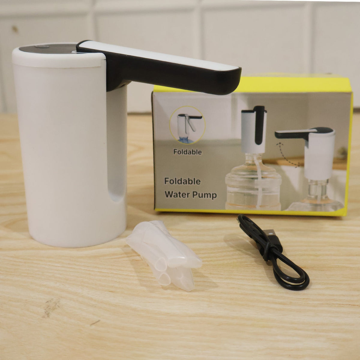 The white and black electric water dispenser pump, a clear silicone tube, and a black USB charging cable are displayed next