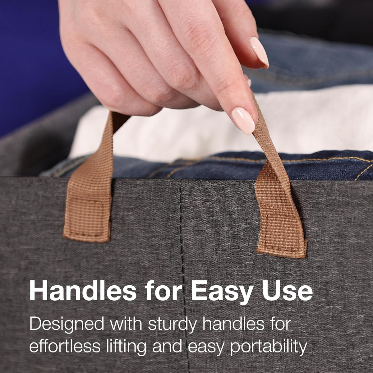 A hand holding the brown fabric handle of a gray storage basket filled with clothes, with text overlay.