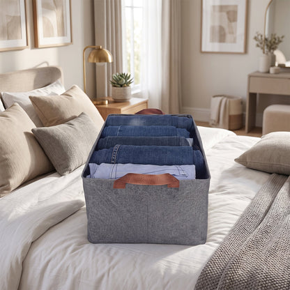A gray foldable fabric storage basket filled with folded clothes on a bed in a bedroom setting.