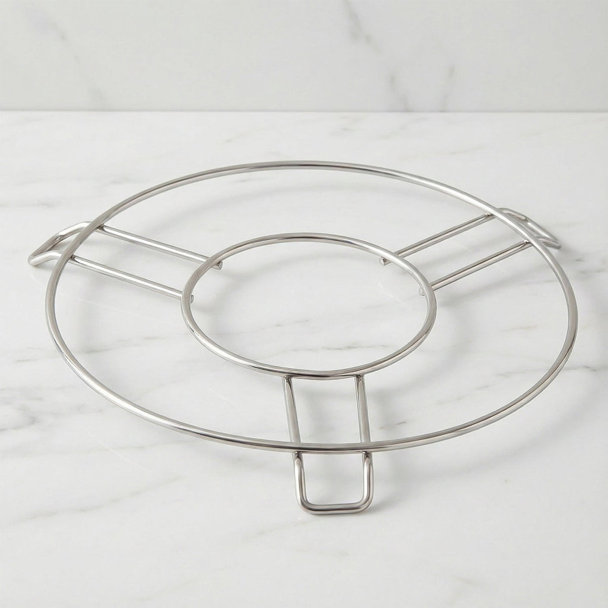 A silver wire hot pot stand is centered on a light grey marble countertop.