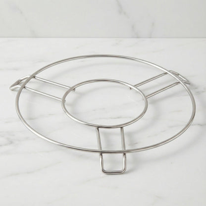 A silver wire hot pot stand is centered on a light grey marble countertop.